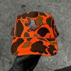 Introducing our laid-back essential, an orange camouflage 5-Panel High Crown Mesh Back Trucker Hat - the epitome of casual comfort and easygoing style. Crafted for leisurely days, this hat features a high crown design and breathable mesh panels, making it your effortless go-to for a relaxed vibe. What sets this cap apart? A personalized ironed Duck Hunt patch on the front. Add a touch of uniqueness that reflects your individuality and style. Whether you're strolling through the city or embracing Casual Camouflage Baseball Cap For Outdoor Activities, Brown Casual Baseball Cap For Hunting, Casual Brown Hat For Hunting, Casual Camouflage Baseball Cap For Outdoor, Casual Brown Hunting Hat, Casual Hunting Hats For Fall, Casual Flat Bill Snapback Hat For Hunting, Casual Fall Hunting Hats, Orange Bucket Hat For Outdoor