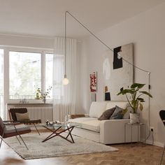 a living room filled with furniture and a large window covered in white curtained curtains