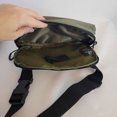 a person holding onto a green bag on top of a white table with black straps