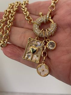 This Equestrian style chain necklace features a CZ mariner clasp with 3 stunning charms. A mother of pearl coat of arms, a mother of pearl clover and a large cubic zirconia stone. The chain is brass, gold plated and is 8mm wide . It is 18k electroplated for a high quality finish. Perfect for layering with other necklaces. Tips to keep your jewelry looking good. 1) Keep jewelry away from water and chemicals. 2) Remove during physical activities. 3) Store separately in a soft pouch or airtight box Clean Fast, Jewellery Art, Hand Knotted Necklace, Mother Of Pearl Jewelry, Shipping Packaging, Gold Necklace Designs, Brass Gold, Knot Necklace, Rolo Chain