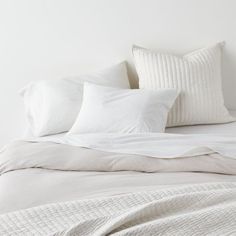 a bed with white sheets and pillows on it