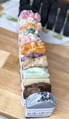 several different types of soaps on a wooden table next to some black and white napkins