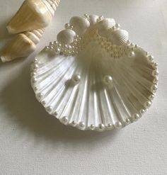 two seashells are sitting on a table next to each other, one is white and the other has pearls