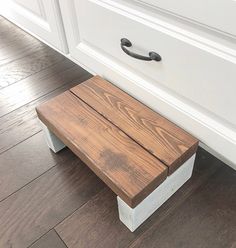 a wooden bench sitting on top of a hard wood floor next to a white cabinet