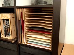 an open book case filled with books on top of a wooden table next to a mirror