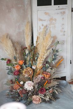 a vase filled with lots of flowers sitting on top of a blue cloth covered table