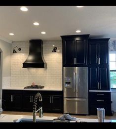 a kitchen with black cabinets and stainless steel appliances