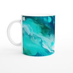 a coffee mug with blue and green paint on it, sitting in front of a white background