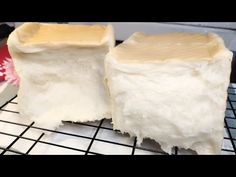 two pieces of white cake sitting on top of a cooling rack next to each other