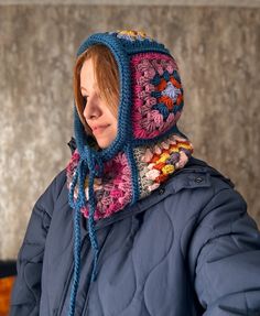 a woman with red hair wearing a blue jacket and a crocheted hat on her head