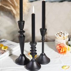 three black candles on a white table cloth