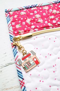 a pink and white flowered purse with a gold keychain attached to it