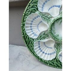 a green and white plate sitting on top of a marble counter next to a wall