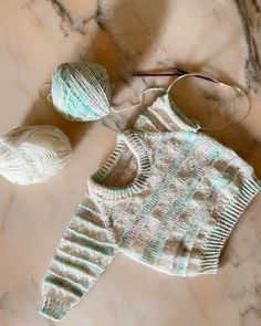 a knitted sweater and ball of yarn on a marble surface