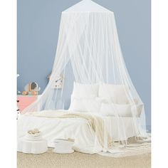 a bed with a white mosquito net over it's head and pillows on the floor