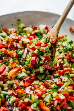 a bowl filled with chopped vegetables and a wooden spoon