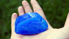 a hand holding a blue rock in it's palm