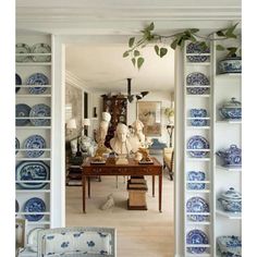 a room filled with lots of blue and white plates on top of bookshelves