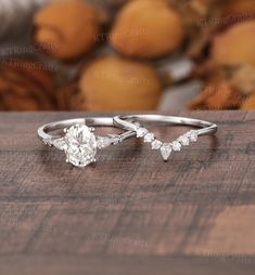 two engagement rings on top of a wooden table with fruit in the backround