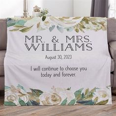 a personalized wedding blanket with flowers on the front and back, is displayed next to a couch