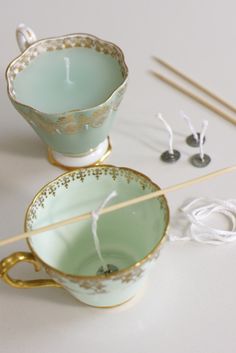 two teacups sitting next to each other with knitting needles in front of them