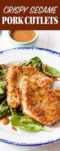 two pieces of fried pork cutlets on a white plate with greens and sauces