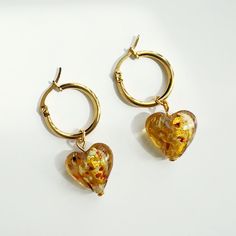 Description   Enhance your style with a touch of funk and flair by wearing these hoops adorned with gorgeous transparent heart charms! These one-of-a-kind earrings add a splash of personality to any ensemble, making you the center of attention. Stand out from the crowd with the charming amber hearts.   Details  * Handmade Earrings  * Length: 1.5 Inches; Width: 1 Inch (approx.)  * Materials: Glass, stainless steel hoop earrings, gold plated findings  * Location: Earlobe  * Closure: Push back  * S Gold Hoop Heart Earrings For Party, Gold Heart Hoop Earrings For Party, Gold Hoop Earrings With Heart Charm For Party, Trendy Gold Heart Earrings With Beads, Trendy Gold Heart Earrings With Heart Beads, Trendy Dangle Earrings With Heart Beads, Gift Hoop Earrings With Heart Beads, Glass Hoop Earrings For Gift, Glass Hoop Earrings Gift