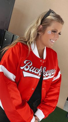 Show them who's boss. The MVP Ohio Varsity Jacket is always one step ahead the ohio varsity jacket featuring a vintage look, collar neckline and long sleeves. Make sure you're prepared to turn heads! Varsity Jacket Ohio varsity jacket Red Ohio game day Vintage gameday look Functional buttons Functional pockets Measurements: Measured laying flat - Approximate S: Bust: 48” | Length: 22” M: Bust: 50” | Length: 22 1/2” L: Bust: 52” | Length: 23” XL: Bust: 54” | Length: 23 1/2” Model Specs: Karli is wearing a size small in the photo. Syd is wearing a size XL.How will this item fit you? Check out our MODEL SPECS (Typical Sizing - Karli: S-Size 5/26 - 5ft 2in, Emily: S-Size 3/25 - 5ft 5in, Syd: L/XL- Size 15/ - 5ft 8in)Need help with sizing? No problem! Join our VIP group on Facebook, Everyday Ch Collegiate Red Outerwear With Letter Print, Red Collegiate Outerwear With Letter Print, Red Long Sleeve Outerwear For Game Day, Red Long-sleeve Outerwear For Game Day, Red Varsity Jacket For Game Day In Winter, Team-colored Long Sleeve Track Jacket For Game Day, Retro Long Sleeve Varsity Jacket For Campus, Red Sporty Outerwear For Game Day, Sporty Red Outerwear For Game Day