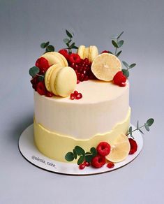 a white cake with lemons, raspberries and orange slices on the top