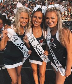 three cheerleaders pose for a photo in front of an audience