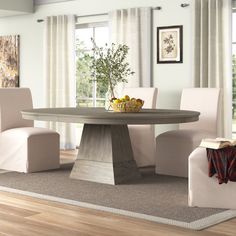 a dining room table with chairs and a bowl of fruit on the table in front of it