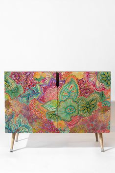 an artisticly painted cabinet with wooden legs