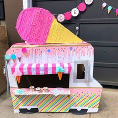 an ice cream cart is decorated with pink, yellow and blue paper mache decorations