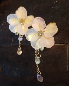 two white flowers are attached to gold chains with crystal drops and dangling beads on them