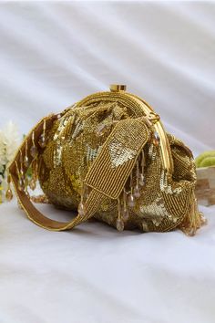 Gold clutch with sequin- cutdana hand embroidery and crystal-beaded hangings along its edge. Comes with embroidered top handle strap.
Type: Embroidered
Composition:  Faux Suede, Velvet
Color: Gold
1 main compartment with small stitched pocket inside
Multi-bead tassels
Closure: Kiss lock clasp
 - Aza Fashions Traditional Bags With Tassels For Reception, Traditional Tassel Bags For Reception, Festive Sequined Bags For Reception, Festive Hand Embellished Gold Bag, Festive Gold Hand Embellished Bag, Festive Gold Hand-embellished Bag, Festive Gold Hand-embellished Clutch, Festive Gold Hand Embellished Clutch, Glamorous Gold Hand-embellished Evening Bag