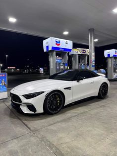 a white sports car parked at a gas station