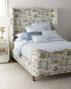 a bed with blue sheets and pillows in a bedroom next to a night stand on a white rug