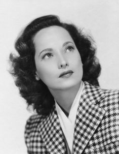 an old black and white photo of a woman with her eyes closed wearing a jacket