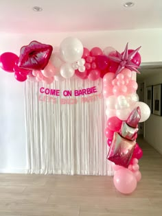 a balloon arch decorated with pink and white balloons, lipstick, and purses for a barbie birthday party