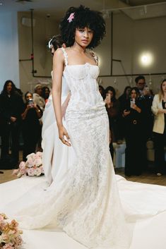 a woman in a white dress walking down a runway