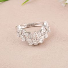 a diamond ring sitting on top of a pink surface next to white flowers and greenery