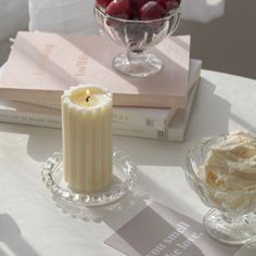 a glass bowl filled with cherries next to a candle on top of a table