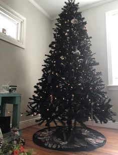 a black christmas tree in a room with wooden floors and white lights on the top