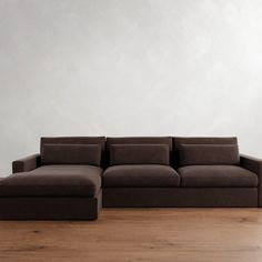 a brown couch sitting on top of a wooden floor next to a white wall in an empty room