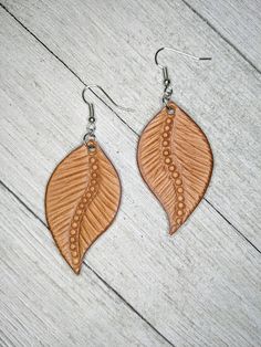 the earrings are made from wood and have leaves on them, with beaded details