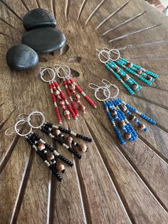 several beaded earrings sitting on top of a wooden table next to rocks and stones