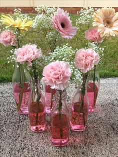 pink and yellow flowers are in vases on the ground