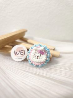 two wooden clothes pins sitting next to each other on a white bed with a name tag