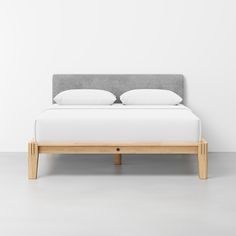 a bed with two pillows on top of it and a white wall in the background