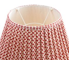 a red and white lampshade with a light on it's bottom half